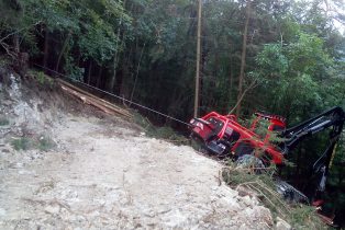 Komatsu 931 angeseilt bei Arbeiten an einer Böschung