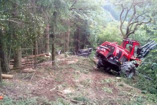 Komatsu 931 angeseilt bei Arbeiten an einer Böschung